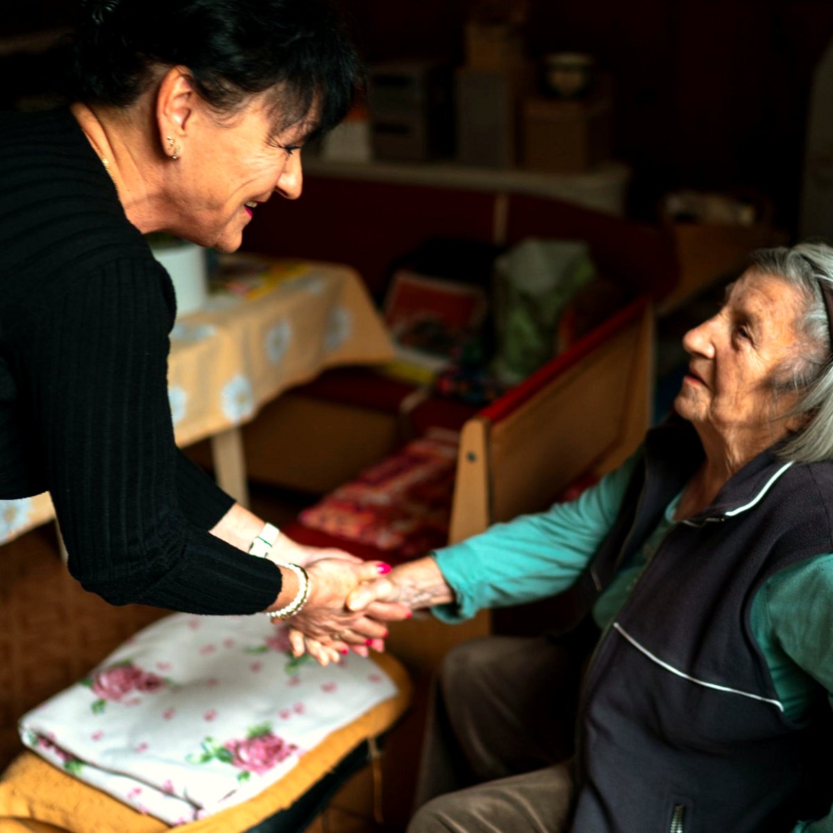 Care worker holding an older woman's hands during a home visit