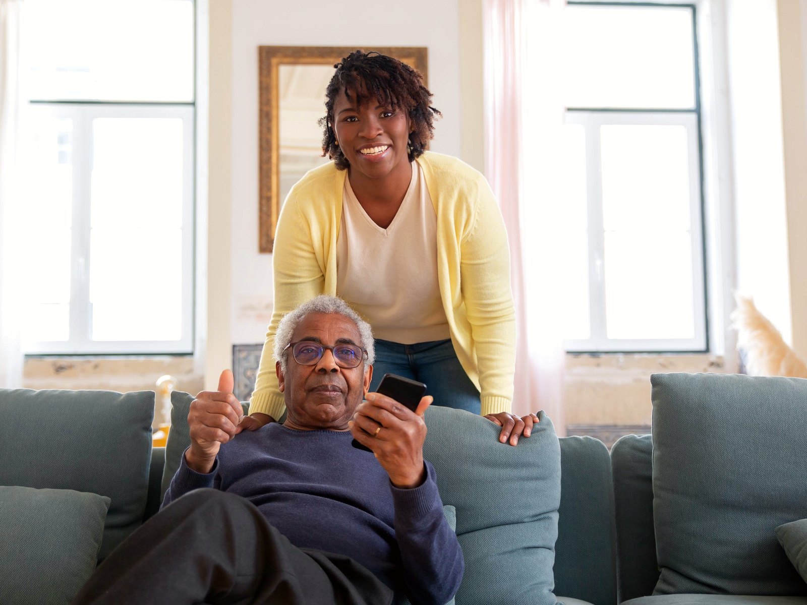 Care worker standing with an older man in his living room