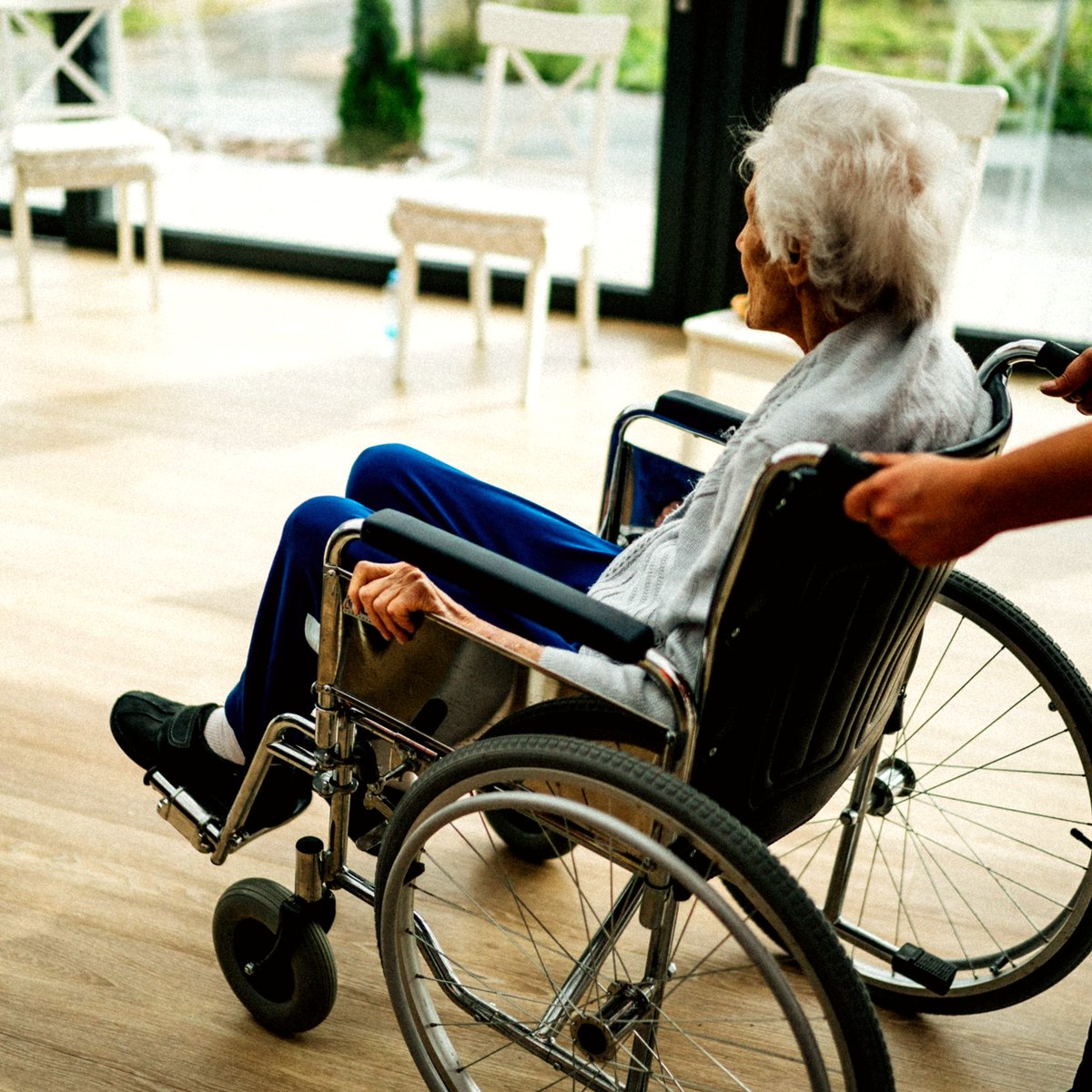 Care worker pushing an older person in a wheelchair